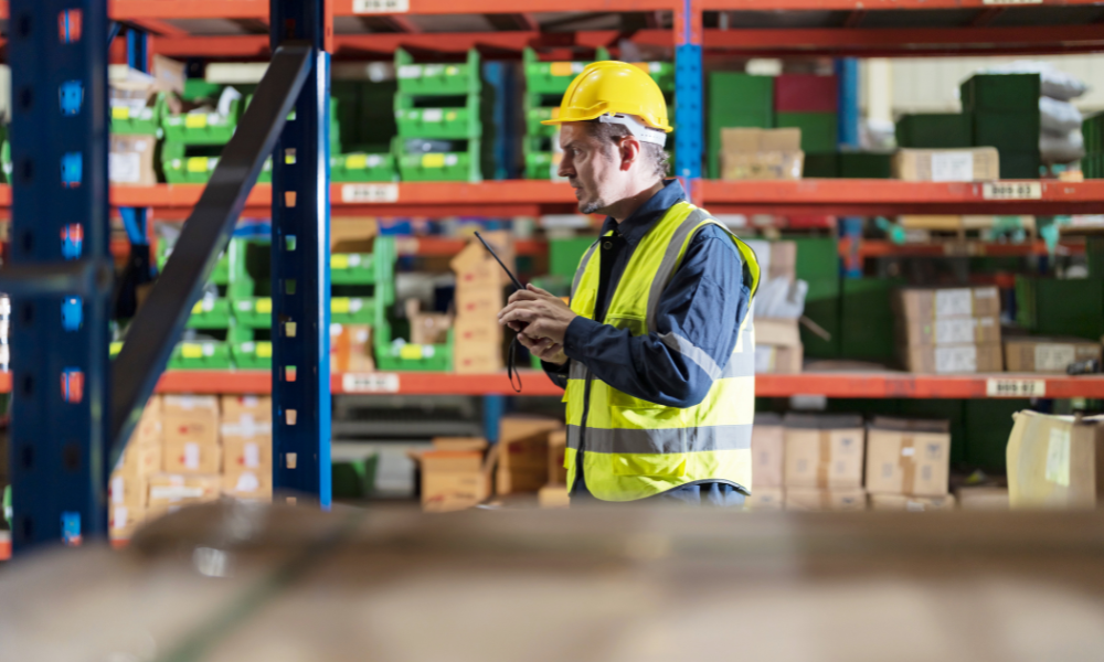 Male employee using a radio in the warehouse.